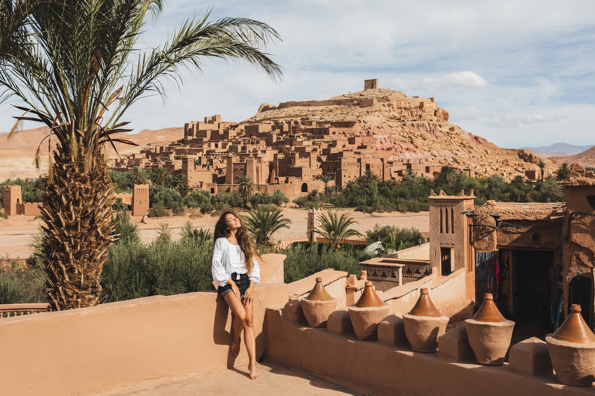 Beautiful young woman happy to travel in Morocco. Ait-Ben-Haddou kasbah on background