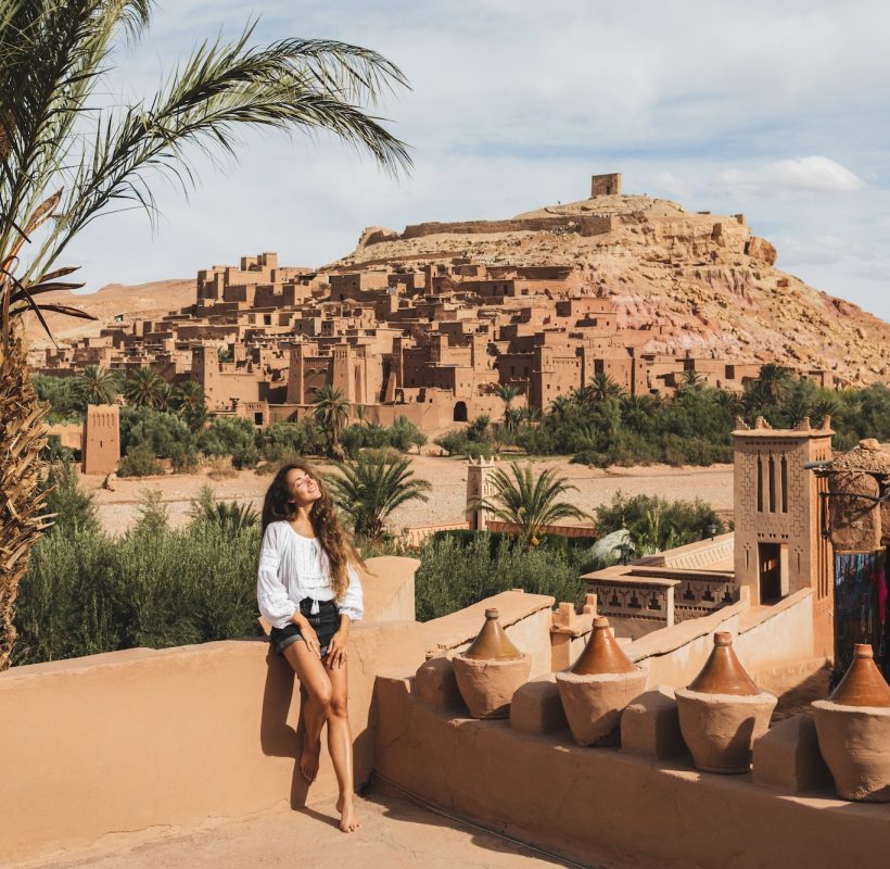 Beautiful young woman happy to travel in Morocco. Ait-Ben-Haddou kasbah on background